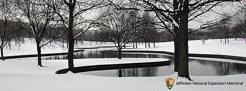 Winter on the Gateway Arch grounds, snow-dusted lawns and bare trees beneath the Arch, a grounds substitute for the food card.