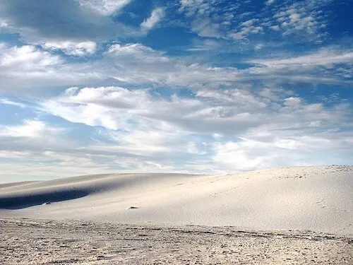 Open white gypsum flat meeting a wide cloud-streaked sky at the edge of the White Sands dunefield.