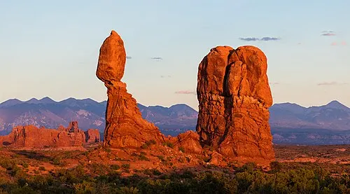Balanced Rock, a 55-foot caprock perched atop a 128-foot sandstone tower, glowing in low evening light.