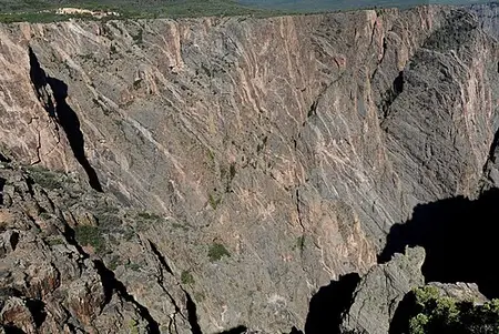 Close view of dark Precambrian gneiss cut by light pink pegmatite veins in the canyon wall.