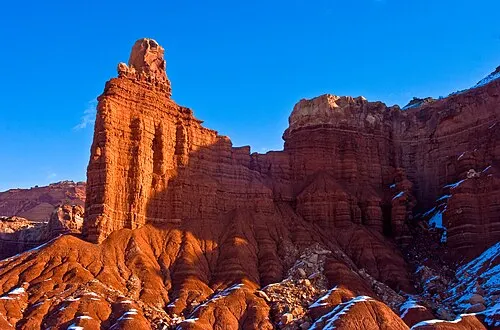 Dark red Moenkopi Formation pinnacle of Chimney Rock standing alone against a clear sky in Capitol Reef National Park.