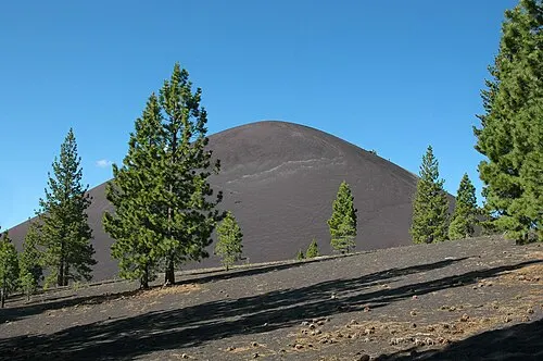 The symmetrical dark cone of Cinder Cone rising from a forested basin in the park's northeast corner.