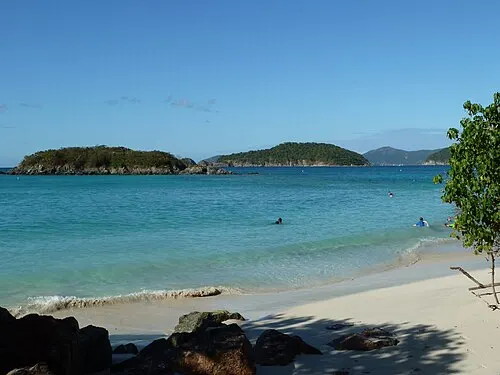 View from Cinnamon Bay beach toward Cinnamon and Whistling Cays across calm North Shore water.