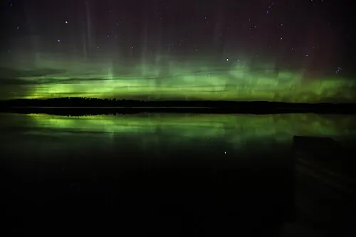 Green northern lights over the dark water of Voyageurs National Park, an International Dark Sky Park.