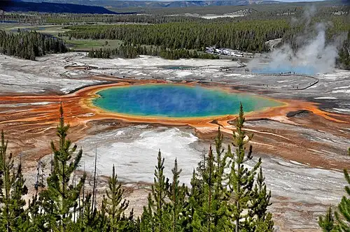 Boardwalk-level view of Grand Prismatic Spring showing the orange microbial mats around a deep blue center pool.
