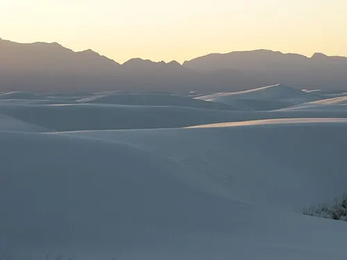 Low sunlight rakes across rolling white gypsum dunes at the heart of White Sands National Park.