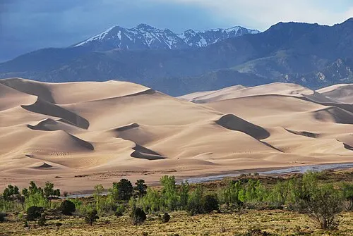 Dunes rising behind Medano Creek with Cleveland Peak of the Sangre de Cristo range above in spring.