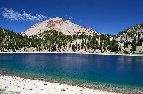 Lassen Peak rising above Lake Helen, snow on the upper slopes, under a clear sky.
