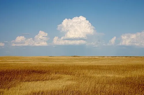 Cumulus clouds building over the mixed-grass prairie tableland above the Badlands wall.