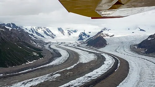 The Kennicott and Root glaciers meeting below the mountains near Kennicott, debris-streaked ice running into clean white ice.