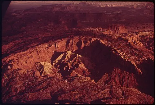 Aerial view of the roughly three mile wide Upheaval Dome crater with tilted rock layers ringing a central uplift.