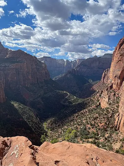 Zion Canyon and the North Fork of the Virgin River seen from high on the canyon wall, red Navajo Sandstone cliffs dropping to a green valley floor.