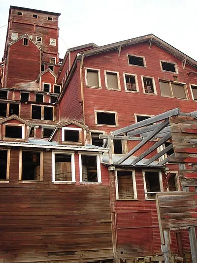 The red 14-story Kennecott copper concentration mill, a National Historic Landmark, standing on the hillside above the Kennicott Glacier.