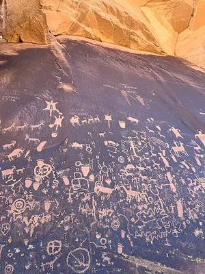 Newspaper Rock petroglyph panel on UT-211, hundreds of figures pecked over roughly 2,000 years by Ancestral Puebloan, Ute, and earlier makers.
