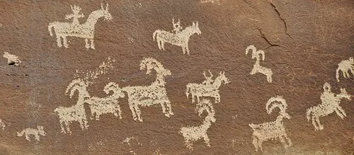 Ute petroglyph panel at Wolfe Ranch carved into desert-varnished sandstone, showing riders on horseback and bighorn sheep, dated post-1600.