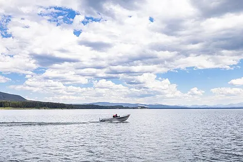 A boater on Yellowstone Lake near Bridge Bay Marina with forested shoreline behind.