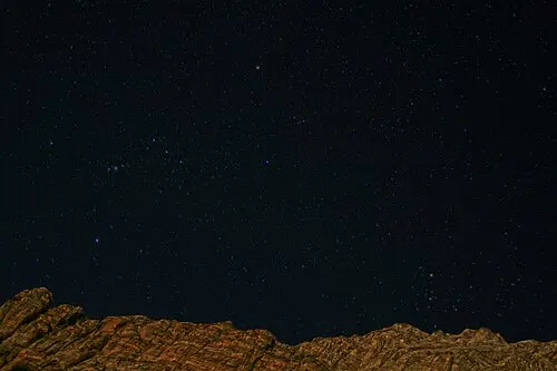 The constellation Orion in a dark night sky above the silhouetted cliffs of Zion, an International Dark Sky Park.