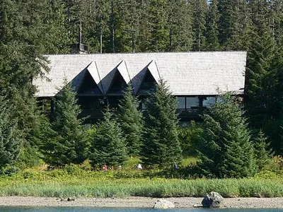 Glacier Bay Lodge seen across the water from Bartlett Cove, set among tall spruce.
