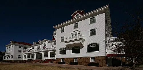 The white 1909 Stanley Hotel on a hill above Estes Park with the Front Range behind it.