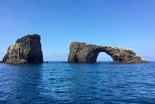 The 40-foot Arch Rock sea arch off East Anacapa Island, with ocean and island cliffs behind it.