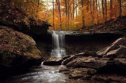 Blue Hen Falls flowing over a sandstone ledge in a wooded gorge at Cuyahoga Valley National Park.