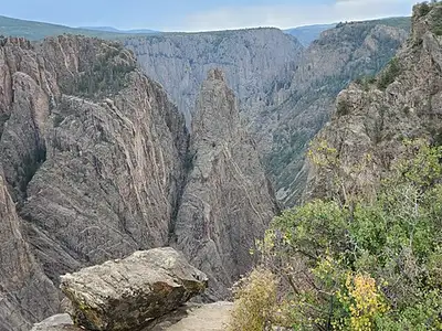 Vertical fissures splitting the canyon rock face seen from a South Rim nature-trail overlook.