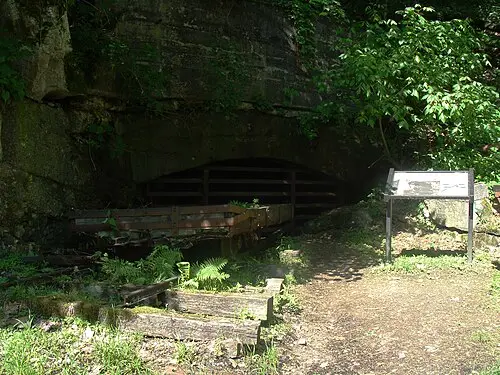 An old mine car standing in front of the preserved Kaymoor mine works at the end of the Kaymoor Miners Trail.