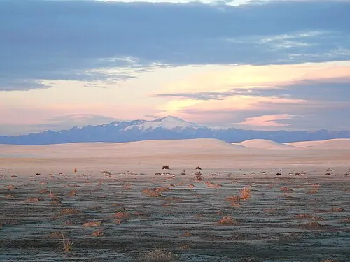 Sierra Blanca rising beyond the flat dunes near the start of Dunes Drive at sunset.