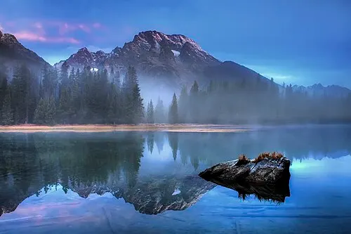 Shallow String Lake with sandy edges and the Teton Range behind, the flat family loop trail tracing the shore.