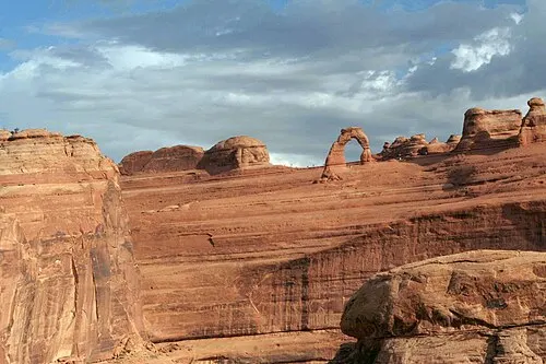 Delicate Arch seen across a canyon from the Delicate Arch Viewpoint, the no-hike option for families skipping the slickrock climb.