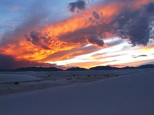Orange and gray clouds at sunset over the White Sands dunefield near the end of Dunes Drive.