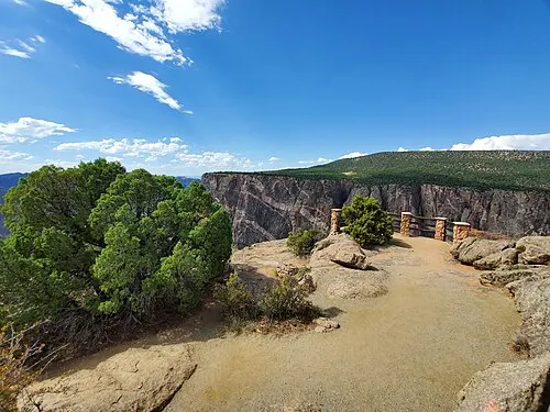 View from a South Rim Drive overlook across the canyon to the opposite wall, pinyon and juniper along the rim.