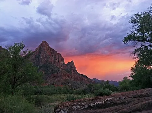 The Watchman peak turning red at sunset above the Virgin River, seen from Canyon Junction Bridge.